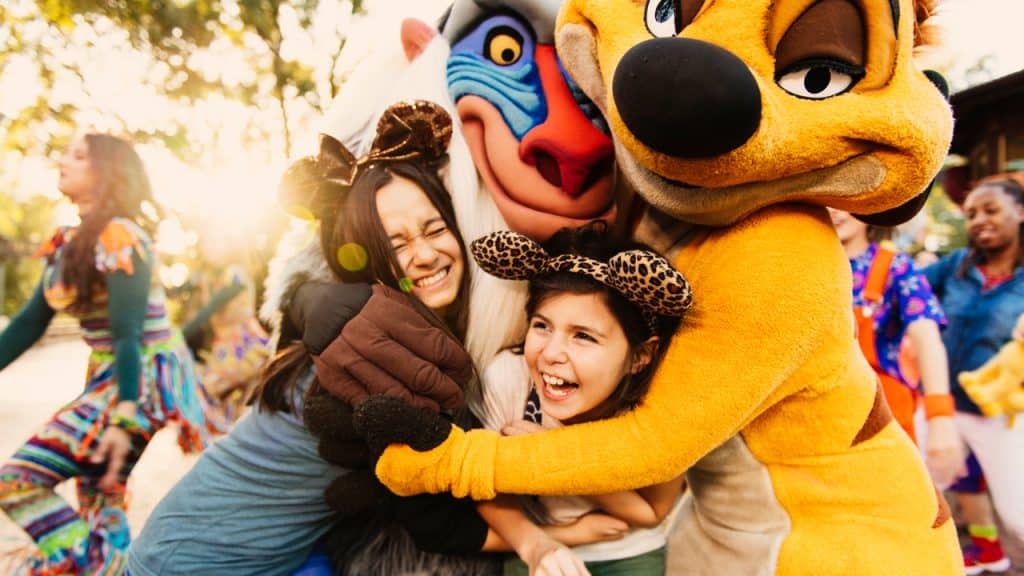 Two girls hug Rafiki and Timon at during the Hakuna Matata Time Dance Party at Disney's Animal Kingdom