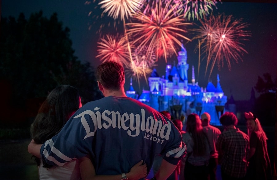 Guests watching fireworks at Disneyland Park wearing a Disneyland Resort spirit jersey