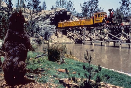 A mine train exits a cave and crosses Bear Country.
