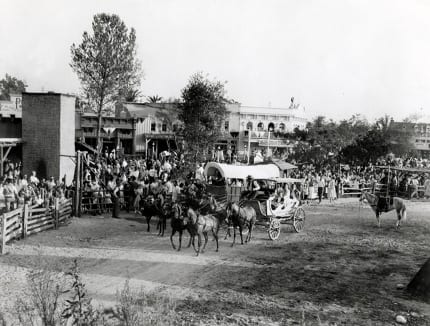 A Conestoga Wagon and Stagecoach prepare to depart through the dusty terrain.