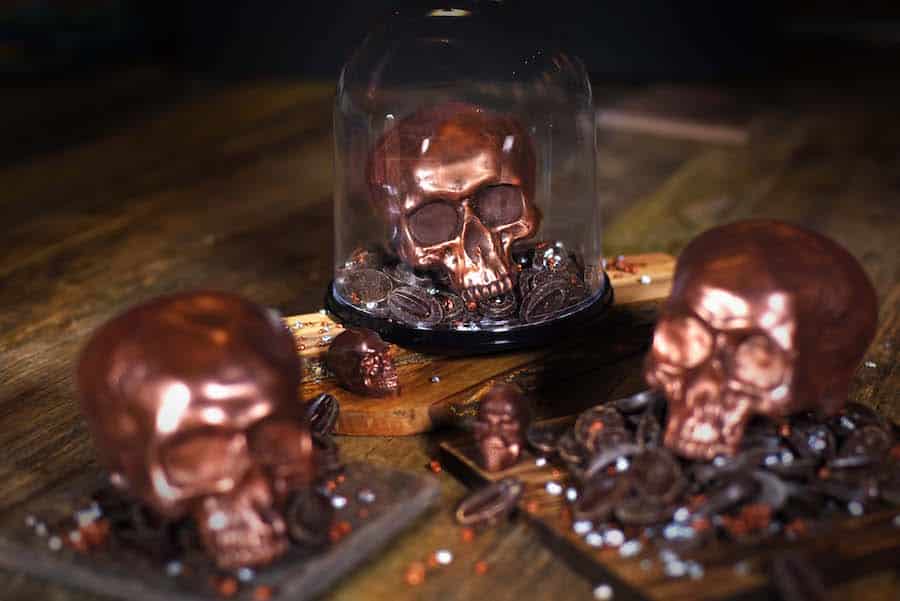 Lorcana New Disney Villains Cards Revealed for Whispers in the Well | The Main Street Mouse the Ganachery Skull Shaped Dark Chocolate for Halloween Season in Glass Case