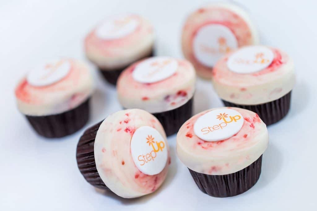 White Chocolate Raspberry Cupcake filled with raspberry compote and topped with raspberry white chocolate frosting with Step Up logo from Sprinkles at Disney Springs