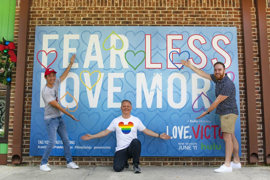 Members of the Disney PRIDE group posing in front of the Love, Victor photo wall in Disney Springs