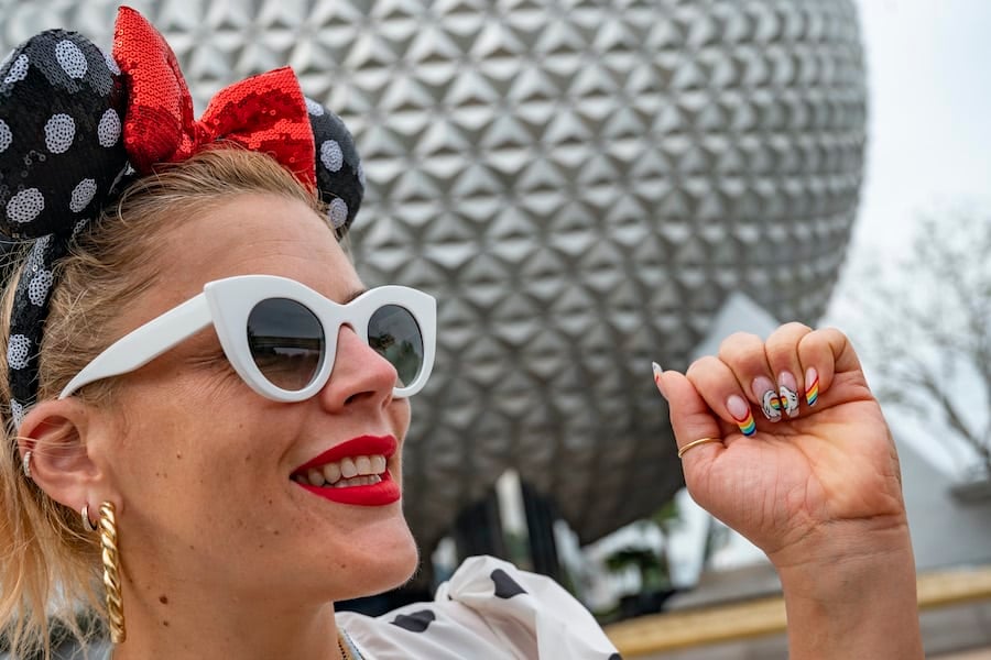 Actress Busy Philipps shows off her Disney-themed PRIDE Month nails in front of Spaceship Earth at EPCOT during a family vacation to Walt Disney World Resort