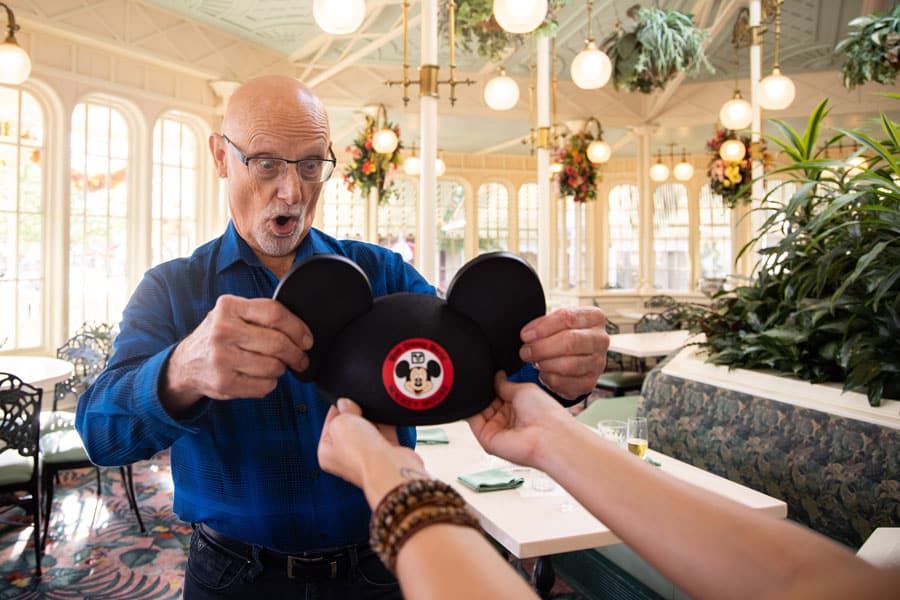 A cast member is presented with a Mickey Mouse ear hat.