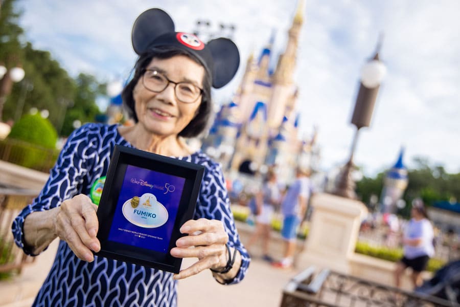 A cast member displays her new nametag in front of Cinderella Castle.