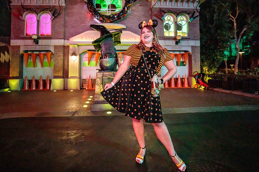 A female cast member in a festive Halloween outfit poses in Radiator Springs