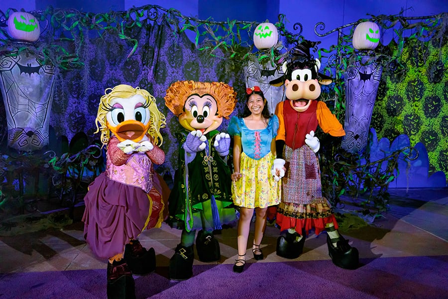 A cast member in a Snow White costume poses with Daisy Minnie and Clarabelle dressed as the Sanderson Sisters