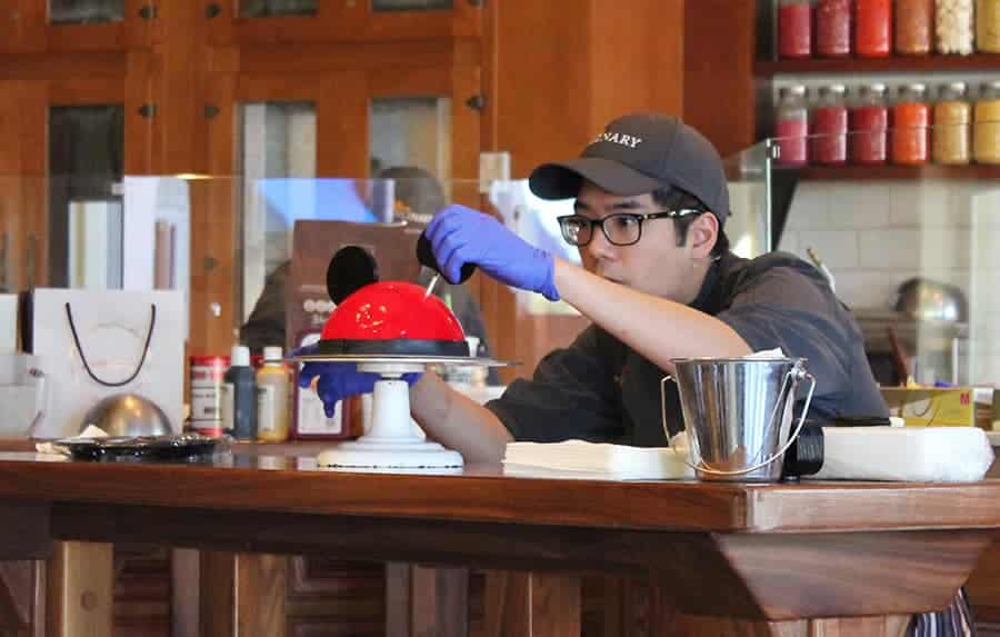 Amorette’s Patisserie cast members decorating a Mickey Dome Cake