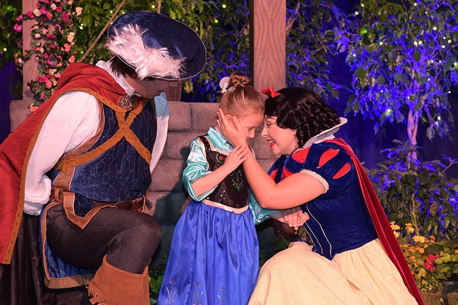 Young wish kid has special moment with Snow White as Snow holds her forehead to forehead Snow White's prince is nearby as well.