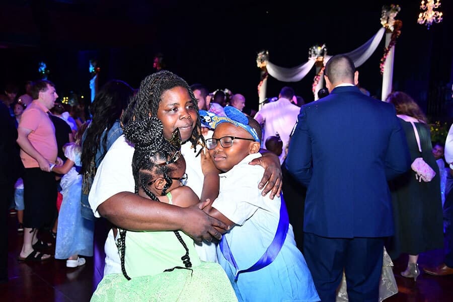 Three school age siblings hug while waiting to meet more Disney princesses