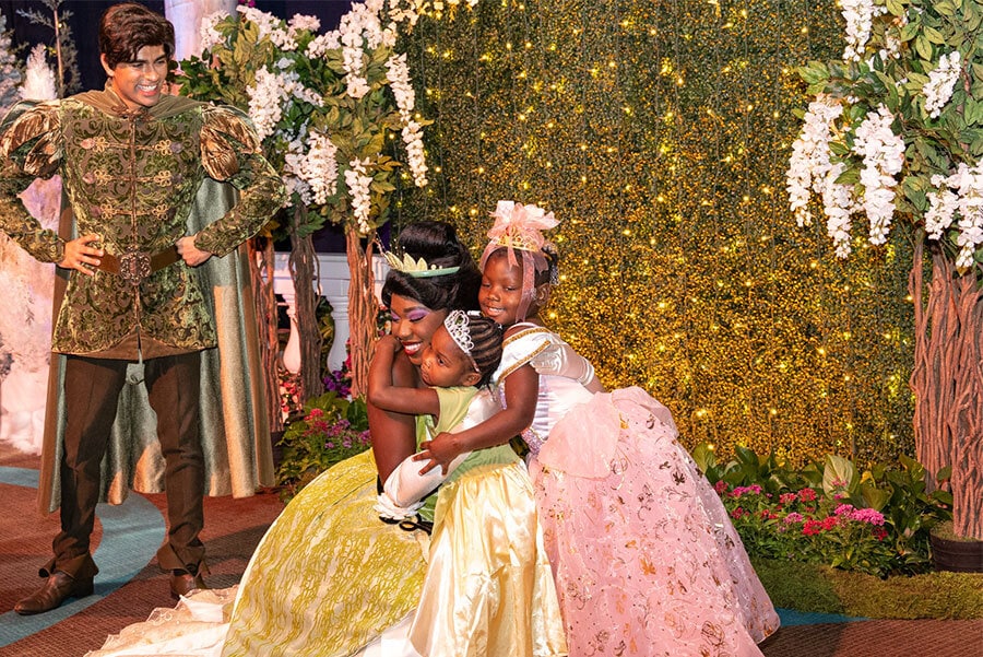 Two young girls hug Tiana with Naveen watching nearby