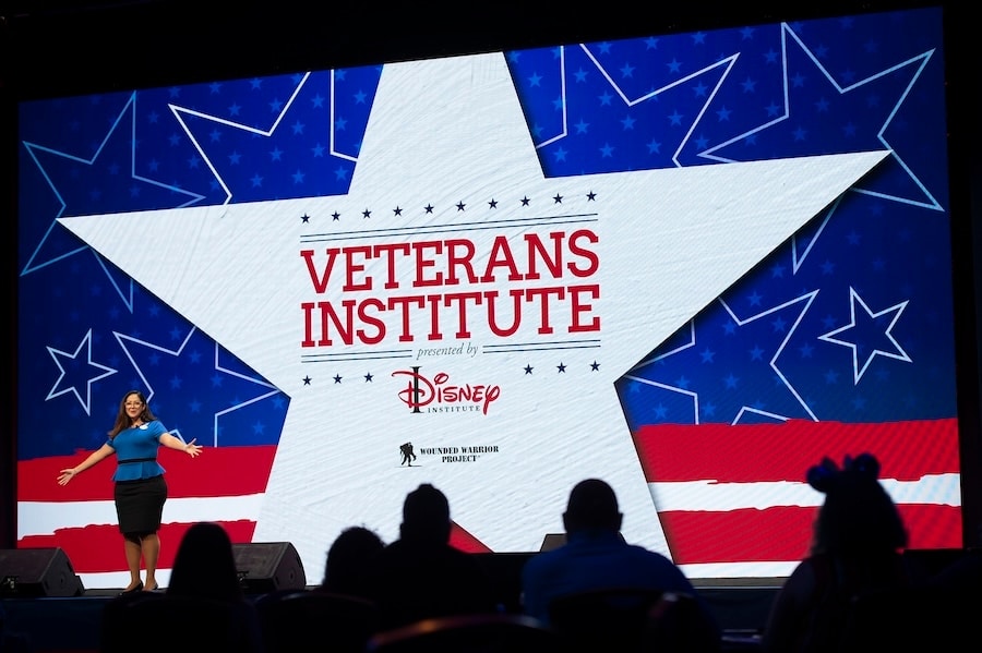 A photo of a Disney Institute cast member on stage speaking at the Veterans Institute Summit held at Disney World Aug. 19-20, 2022