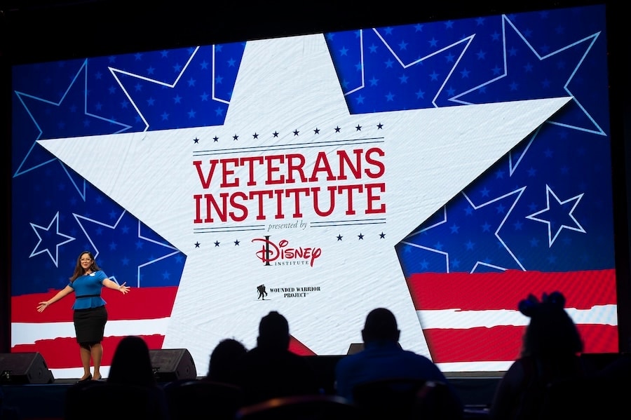 A photo of a Disney Institute cast member on stage speaking at the Veterans Institute Summit held at Disney World Aug 19 20 2022