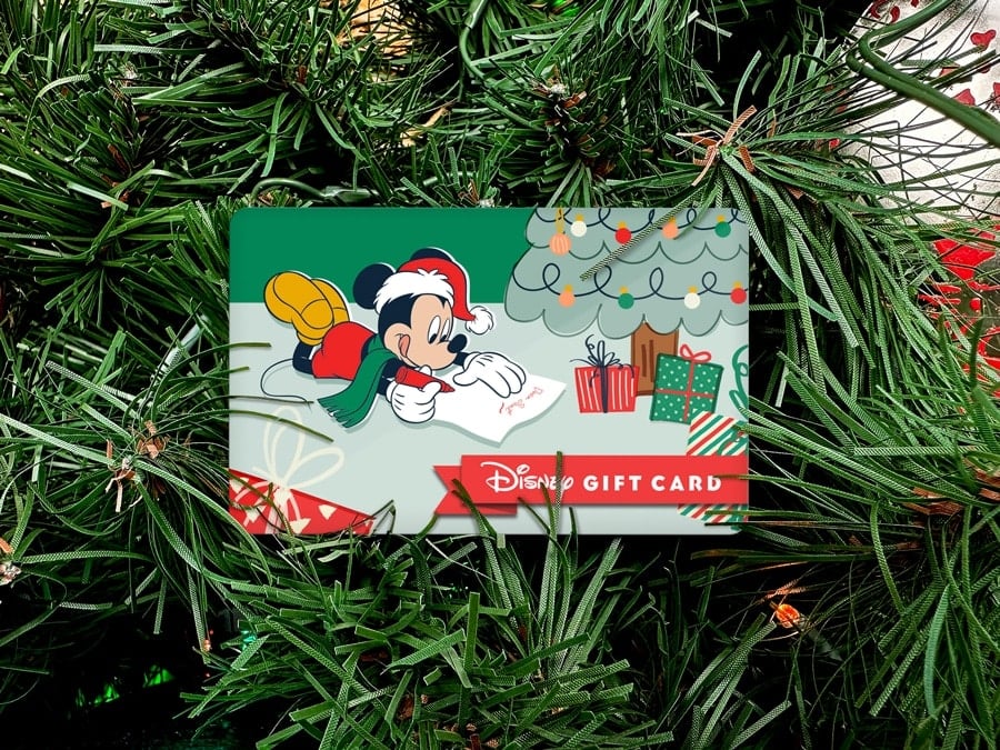 Disney Gift Card 2023 Holiday Gift Card featuring Mickey Mouse laying next to a Christmas tree writing a letter to Santa