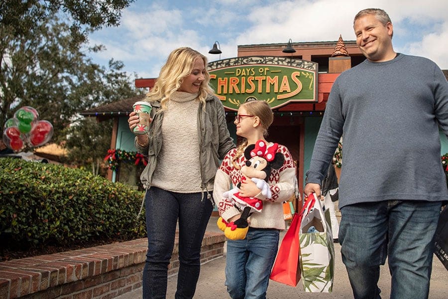 A family shopping at Disney Springs in front of the "Days of Christmas" store