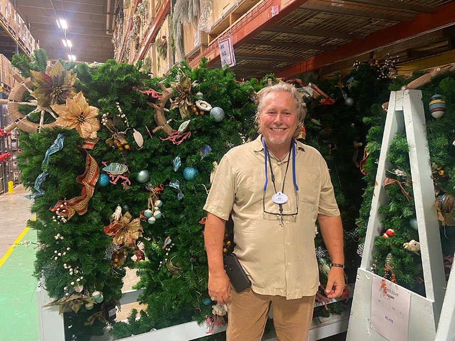 Ed smiles in front of a cart of holiday decorations for Disney's Yacht and Beach Club Resorts.