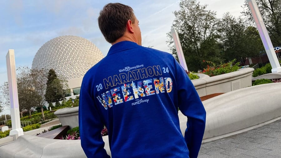 a man at Epcot wearing a 2024 marathon weekend long sleeve merchandise