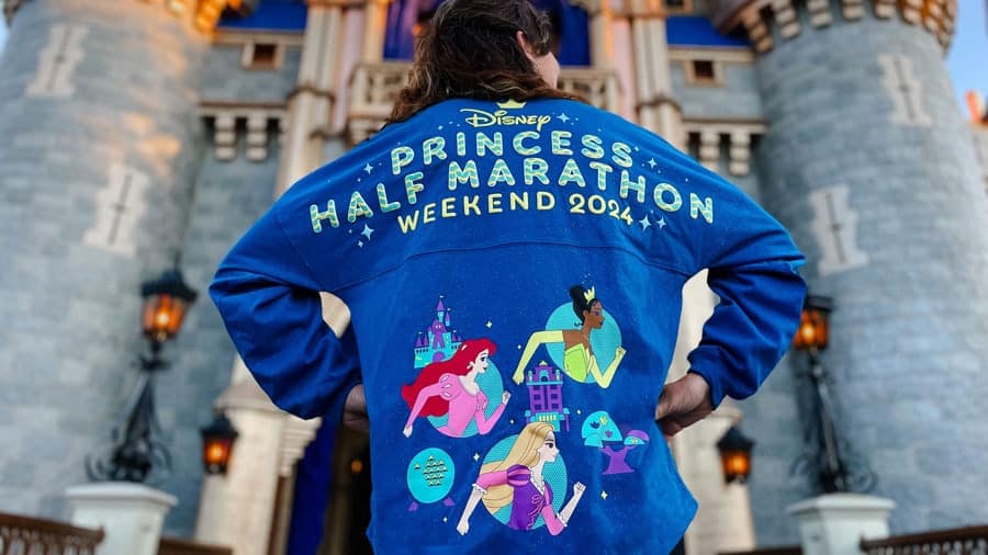 person in front of cinderella's castle wearing a themed princess half marathon weekend 2024 spirit jersey