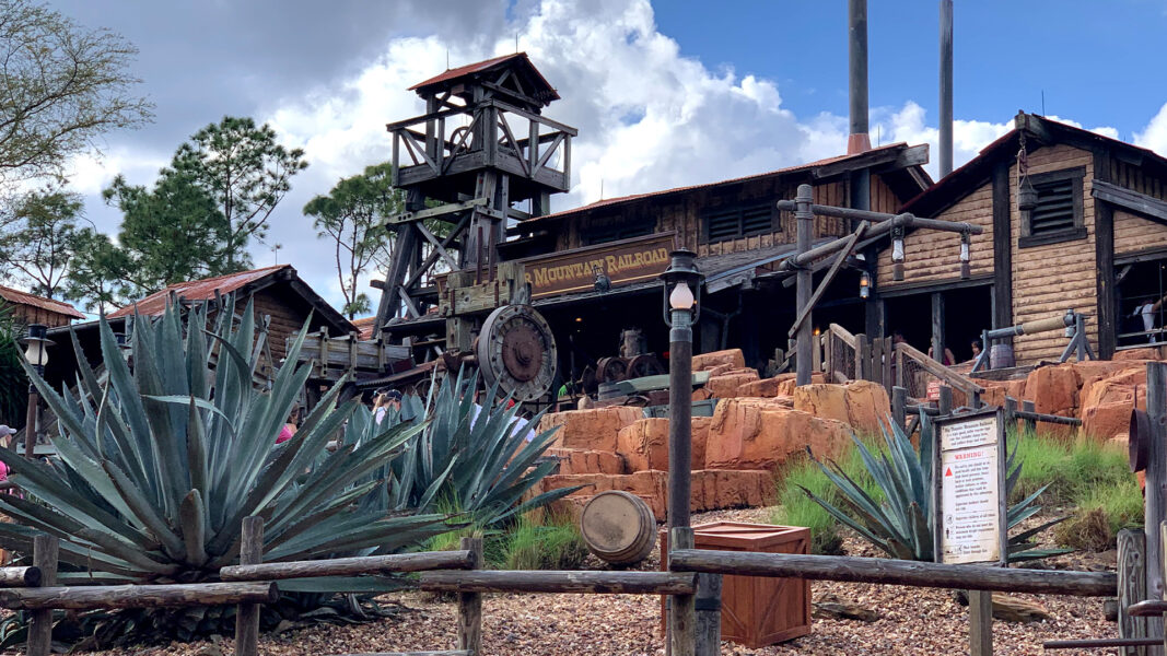 Rustic frontier railroad station with a tall wooden lookout tower weathered buildings and rock landscaping