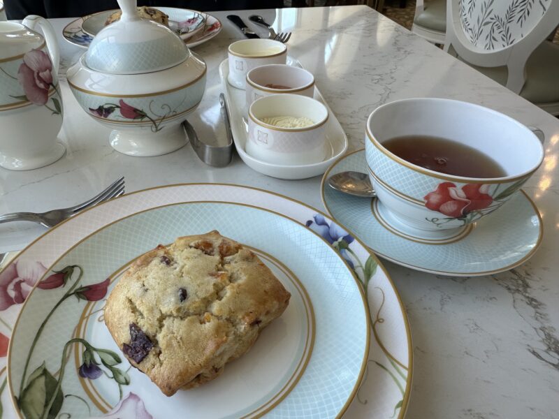 Tea service and scone on a marble table matching floral china teapot cups and plates set for tea time