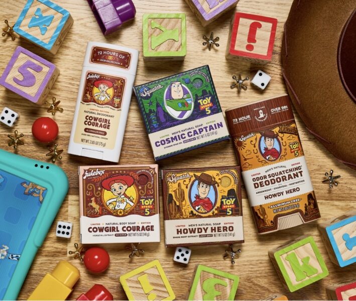 Assortment of Toy Story 5 themed soap boxes and deodorants on a wooden surface with colorful blocks and dice nearby