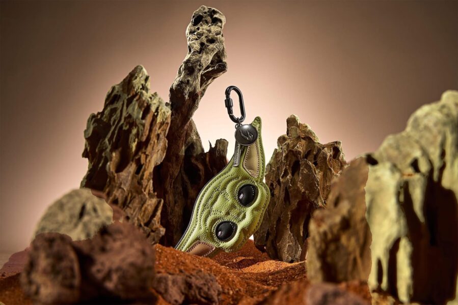 Green hiking boot with a metal carabiner attached perched on jagged rocks against a warm backdrop