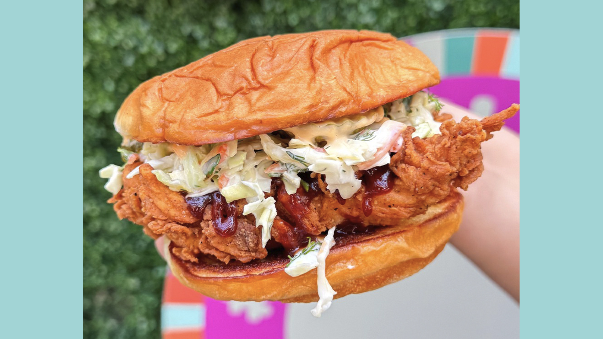 Crispy Fried Chicken Sandwich with Creamy Coleslaw and Sauce in a Soft Bun Held Outdoors