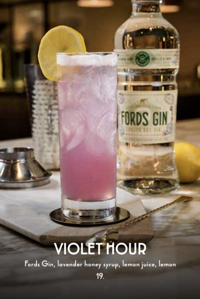 Pink Lavender Cocktail with a Lemon Wedge Beside a Fords Gin Bottle on a Bar Top