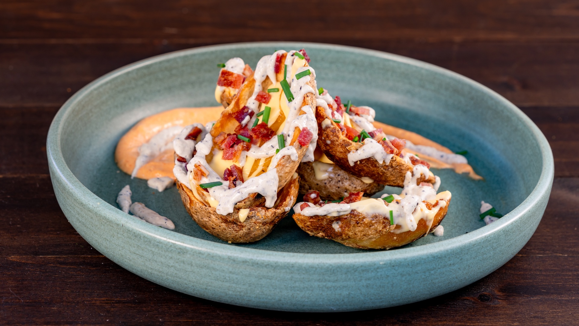 2026DXA250FoodieGuidePotatoSkins | The Main Street Mouse Two Pot2026 dx a250 foodie guide potatoskinsato Skins on a Teal Plate Topped with Melted Cheese Sauce Bacon Bits and Chopped Chives