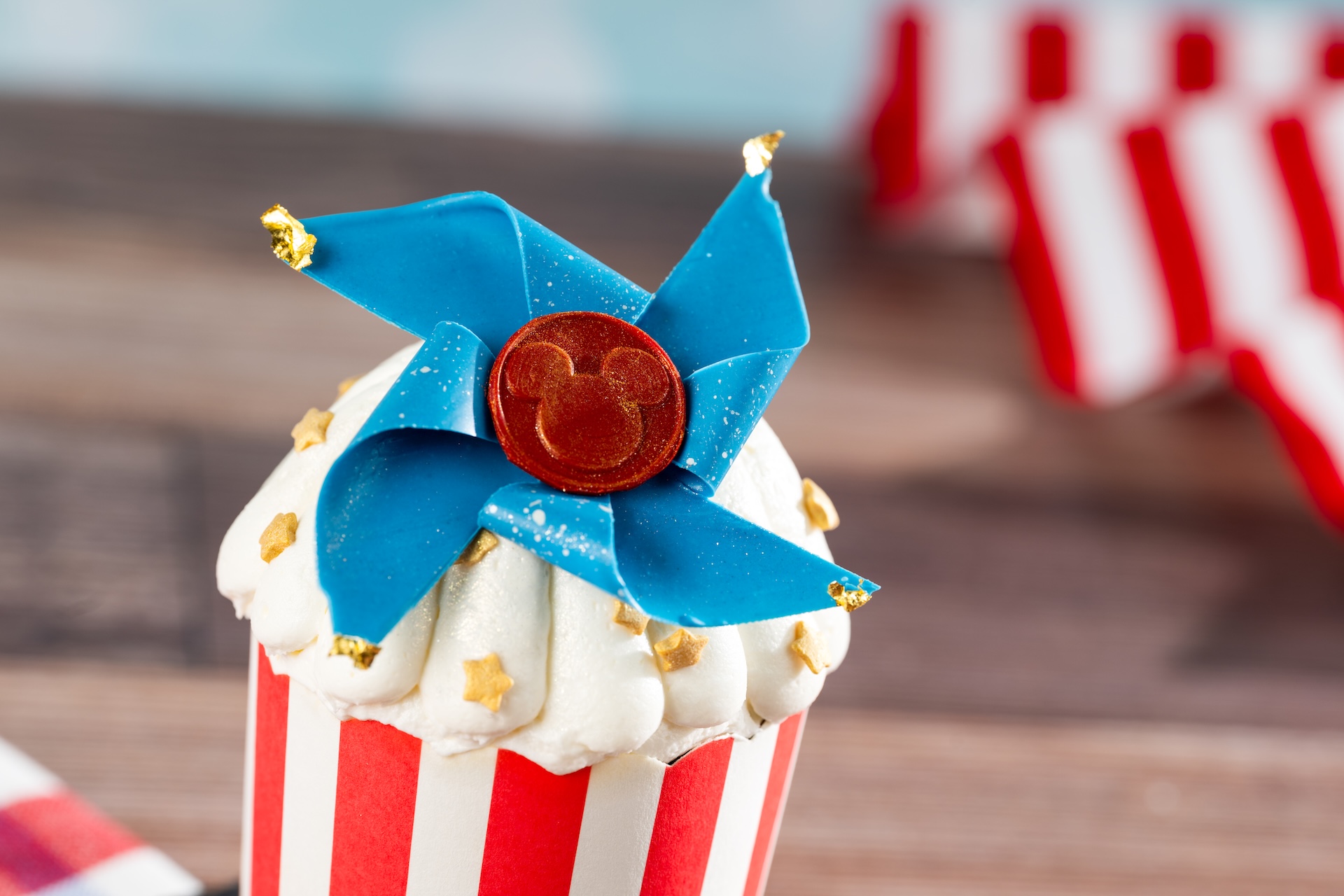 Cu Strawberryshortcakecupcake Pcake with White Frosting in a Red and white Striped Cup Topped by a Blue Bow and a Red Mickey Mouse Coin Decoration