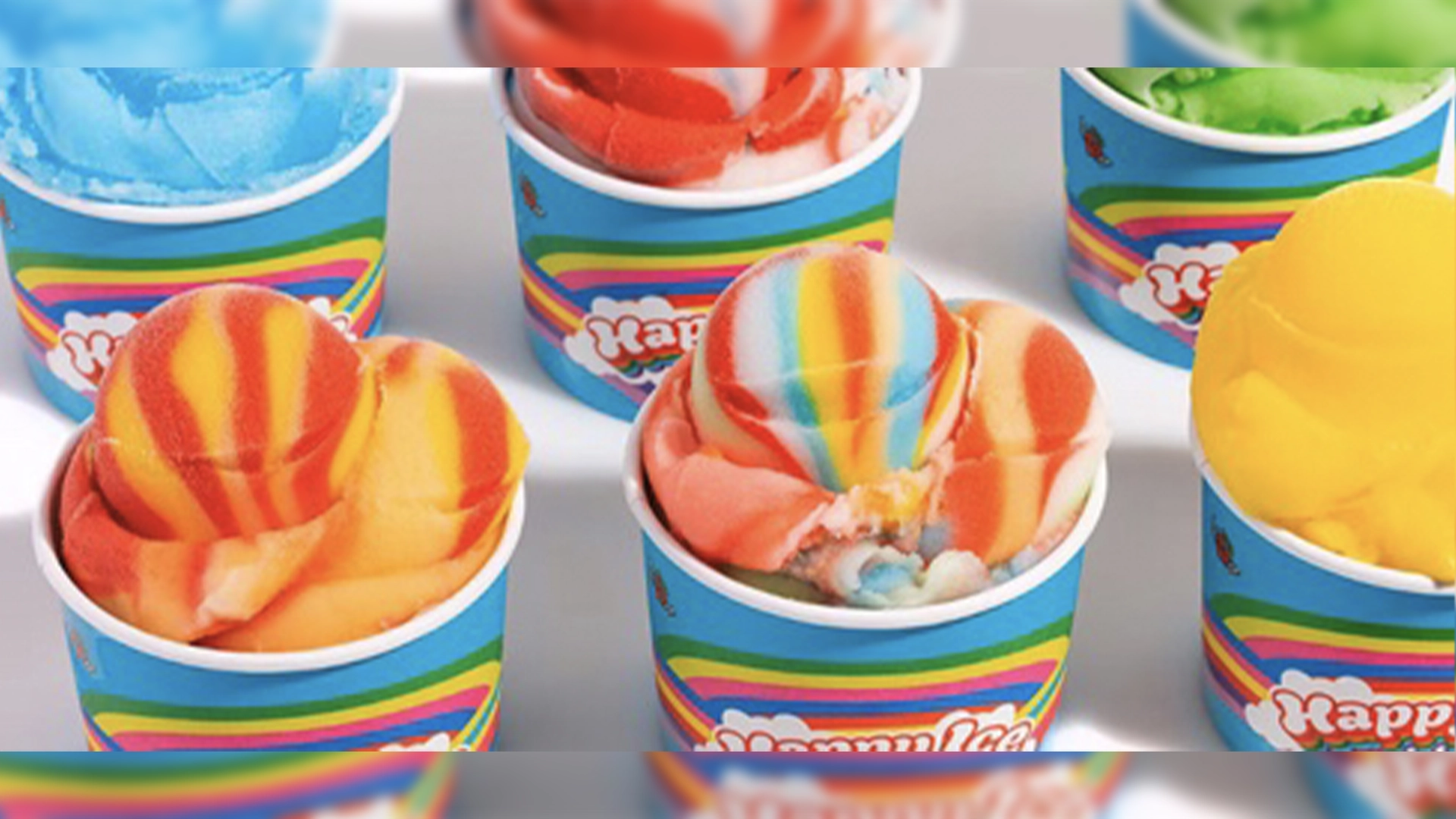 Happy Ice Brings a Colorful New Frozen Treat Experience to Downtown Disney | The Main Street Mouse Colorful Cups of Rainbow Swirl Ice Cream Arranged in a Grid Bright Blue Wrappers with Rainbow Stripes Visible on Each Cup
